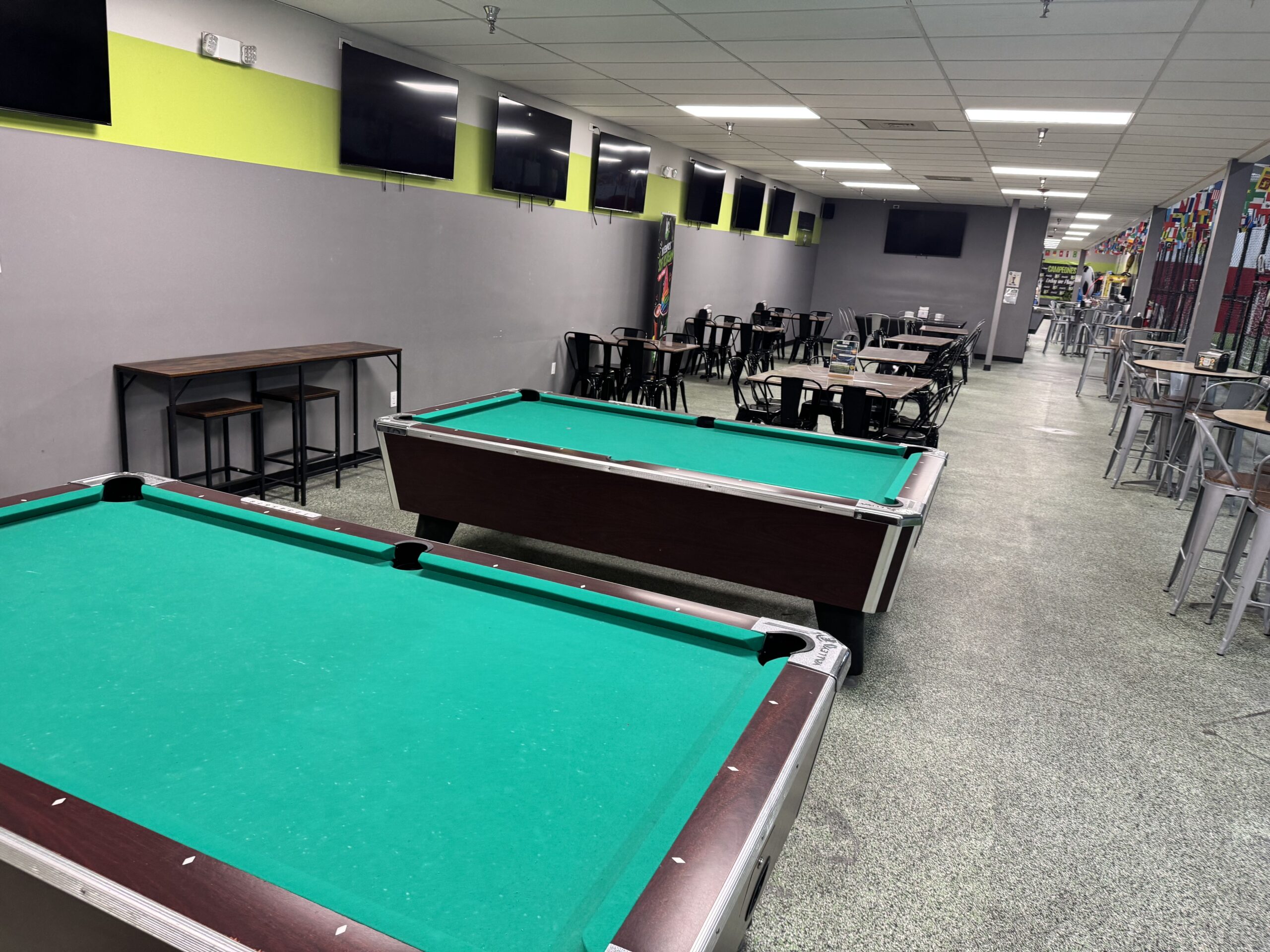 Seating area with tables, screens and pool tables for families at the Lake Worth indoor soccer facility