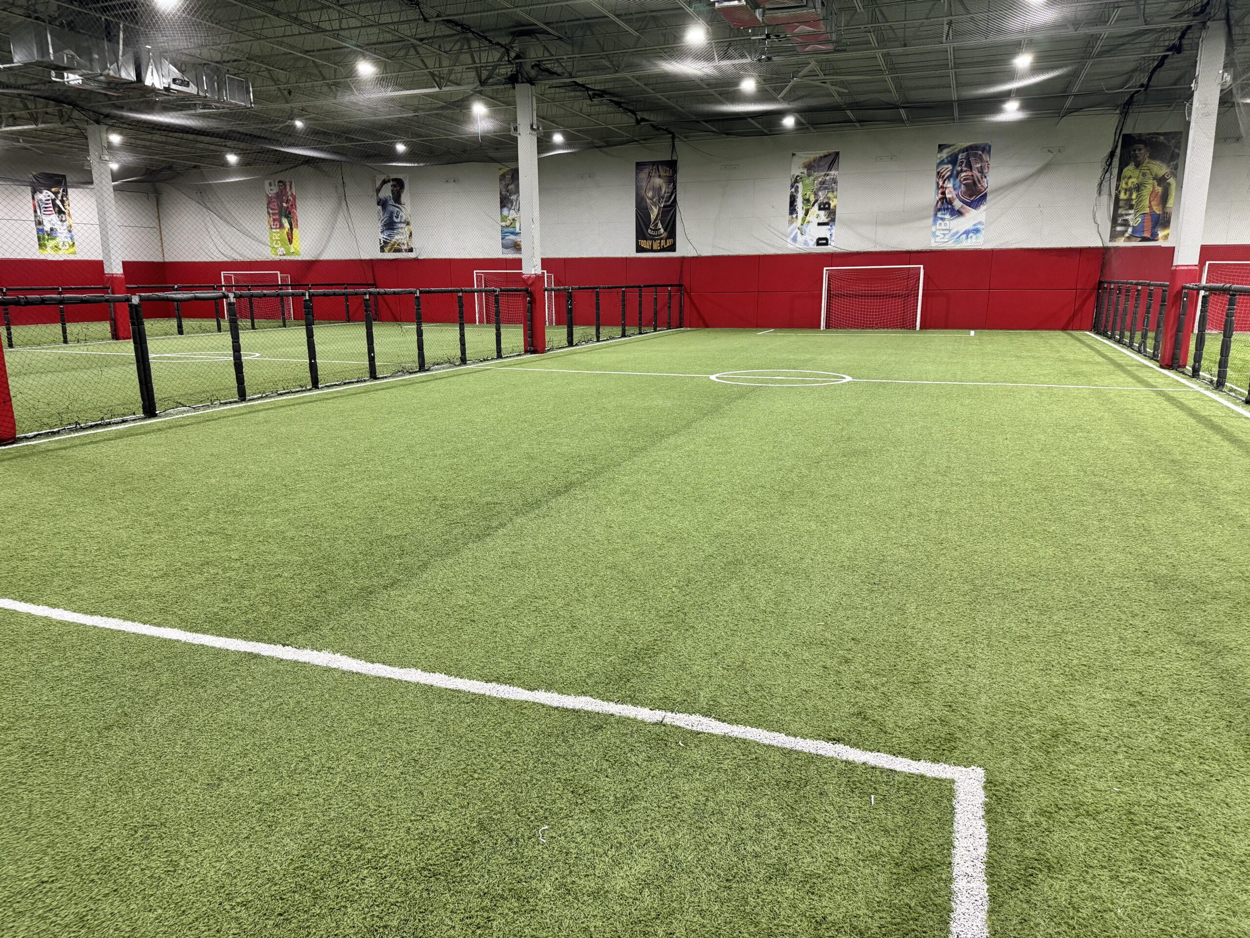 Full size indoor soccer pitch with red padded walls at the Lake Worth facility